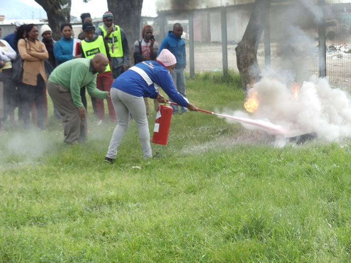 Participant demonstrating how to use a fire extinguisher in the Community Based Home Fire Saftey workshop