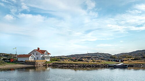White wooden house with a small beach and an old motorboat in Norra Grundsund, Lysekil Municipality, Sweden.