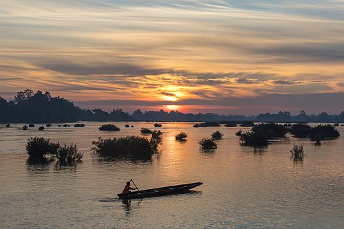 Silhouette of a fisherman on his pirogue at sunrise in Si Phan Don Laos