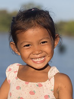 Young girl smiling with teeth in sunshine at golden hour, in Don Det (Si Phan Don), Laos