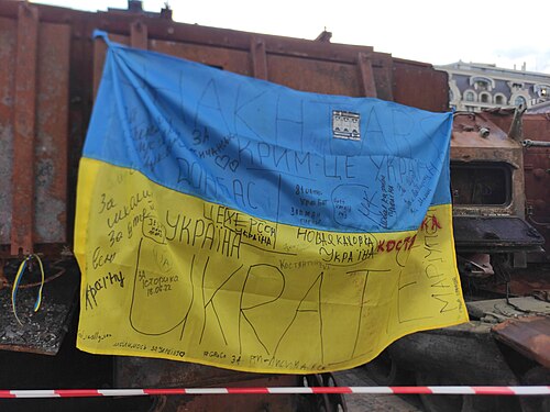 Ukrainian flag on burned enemy equipment. Kyiv. Mykhailivska Square. September 2022