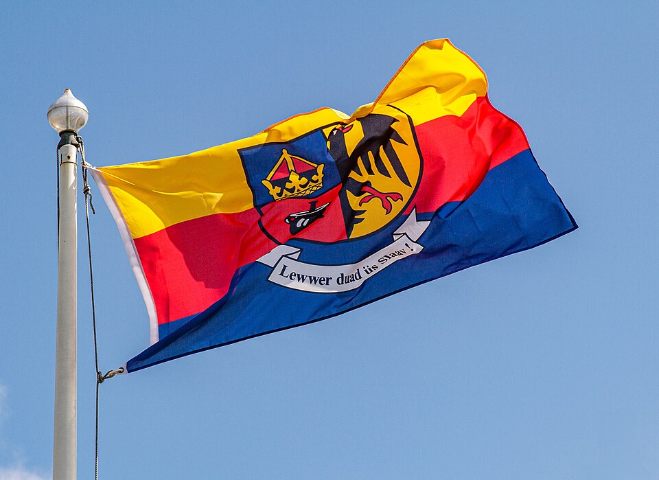 Flying flag of North Frisia with coat of arms and political motto "Better dead than a slave!"