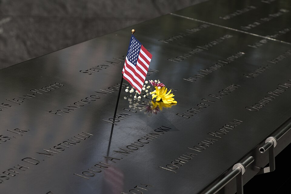 US flag and engraved victims' names at National September 11 Memorial, Ground Zero, New York, USA