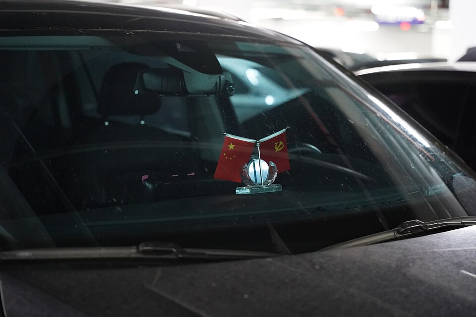 Flags of the People's Republic of China and the Communist Party of China on a car dashboard