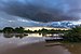 Blue stormy clouds at sunset with water reflection and a pirogue moored to the bank, in Don Det, Laos.jpg
